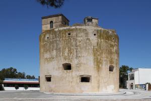 an old stone tower sitting in the middle of a street at La Terrazza sul Mare - Sa Murta Apartments in Torre Grande