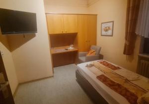 a bedroom with a bed and a chair and a television at Moselbrücke - Serviced Apartments in Wincheringen