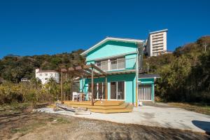 a blue house with a deck in front of it at Sotoura Sunrise Cottage 30m from Beach in Shimoda