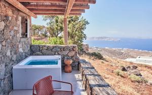 a patio with a hot tub and a chair at Hotiday Mykonos Fanari in Mikonos