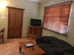 Apartments at Blue Seas Resort في بروم: غرفة معيشة بها أريكة وتلفزيون