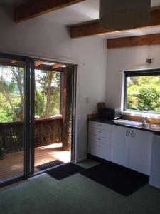 a kitchen with a view of a deck with a window at Cabbage Tree Chalet in Parapara 