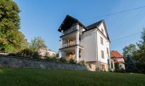 a large white house on a hill with green grass at Apartamenty Watra in Rabka