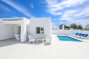 a white villa with a pool and a table and chairs at Villa Garasa in Cala Blanca