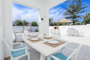 a white dining room with a white table and chairs at Villa Garasa in Cala Blanca