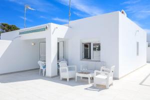 a white house with white chairs and a table at Villa Garasa in Cala Blanca