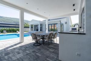 a patio with a table and chairs next to a pool at Villa Mirage in Blagaj