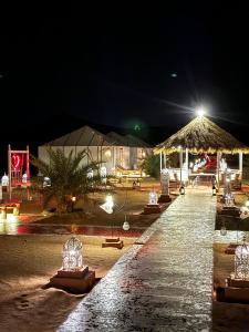 a long walkway with lights at a resort at night at Morocco desert camp in Merzouga +33 photos
