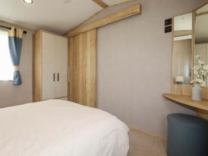 a bedroom with a white bed and a wooden wall at Coastal Escape in Par
