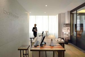 a woman standing in a room with a desk with a laptop at Balthazar Hotel & Spa Rennes - MGallery Collection in Rennes +206 photos