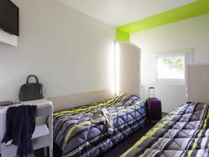 a room with two beds and a tv and a window at hotelF1 Epinal Nord in Épinal