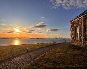 a building on the shore of a body of water at Foxglove Cottage in Killean