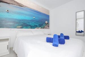 a bedroom with a white bed with a painting on the wall at Villa Izarenar in Cala Blanca +15 photos