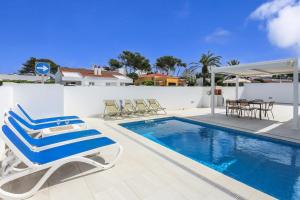 a pool with lounge chairs and a table and a table and chairs at Villa Izarenar in Cala Blanca