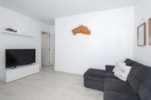 a living room with a black couch and a flat screen tv at Villa Izarenar in Cala Blanca