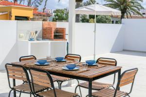a wooden table and chairs on a patio with an umbrella at Villa Izarenar in Cala Blanca