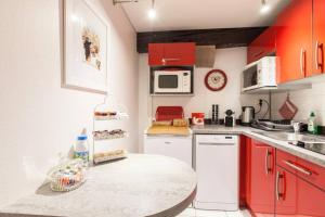 una cocina con armarios rojos y una mesa. en Le Cocon Petite France, en Estrasburgo
