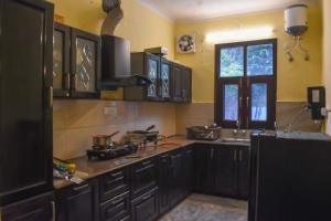 a kitchen with black cabinets and a sink and a window at Pinewood Manor in Dagshai