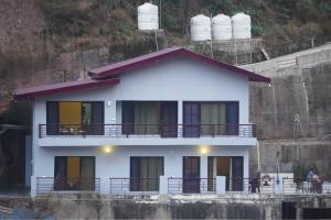 a white house with a balcony and water tanks at Pinewood Manor in Dagshai