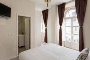 a bedroom with a white bed and a window at Suites Guest House in Cascais