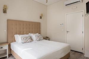 a white bedroom with a large white bed with pillows at Suites Guest House in Cascais +60 photos