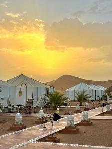 a group of tents in the desert at sunset at Morocco desert camp in Merzouga