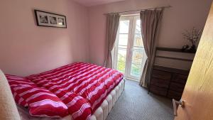 a bedroom with a red and white bed and a window at Modern 2 bed flat with parking by Bluewater shopping mall in Greenhithe