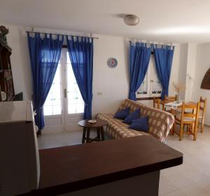 sala de estar con cortinas azules y sofá en Apartamento 2ª planta Ca'n Miquel, en Cala Galdana