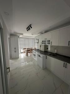 a kitchen with white cabinets and a table in it at Santana Suıts in Trabzon