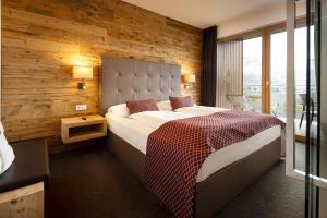 a bedroom with a large bed with a wooden wall at Hotel Der Heinrichshof in Lagundo