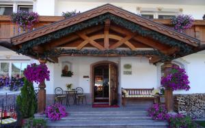 Hotel Garni Concordia - Dolomites Home في سيلفا دي فال جاردينا: جناح مع طاولة وكراسي وزهور