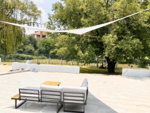 a table and two white benches in a park at RiverfrontOasis - Huge Backyard, Pool, Grand Piano in Sandton