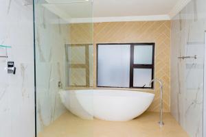 a white bath tub in a bathroom with a window at RiverfrontOasis - Huge Backyard, Pool, Grand Piano in Sandton +23 photos
