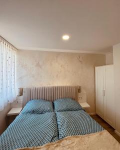 a bedroom with a bed with a blue comforter at Theodora Apartman in Zánka