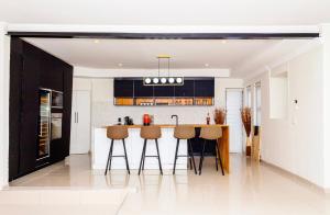 a kitchen with black and white cabinets and a bar at RiverfrontOasis - Huge Backyard, Pool, Grand Piano in Sandton