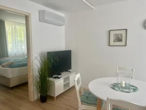 a white living room with a table and a television at Theodora Apartman in Zánka +3 photos