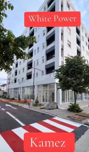 a building with a red and white stripe on the street at White Apartment in Kamëz