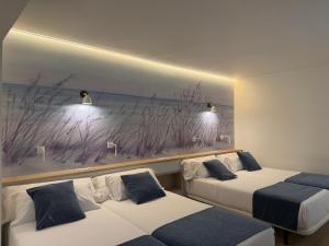 two beds in a room with a painting on the wall at Hotel Plaza Cavana in Nerja +187 photos