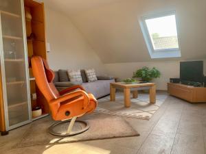 an orange chair in a living room with a couch at Kiebitz Schmuckstück in Walibo in Lippstadt