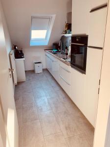 a kitchen with white cabinets and a tile floor at Kiebitz Schmuckstück in Walibo in Lippstadt +6 photos