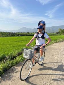 a man riding a bike with a child on his back at Mường Lò Retreat Nghia Lo in Yên Bái