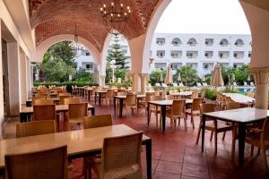 an empty restaurant with tables and chairs and a building at Zodiac Hôtel & Aqua Park in Hammamet