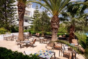 a patio with tables and chairs and palm trees at Zodiac Hôtel & Aqua Park in Hammamet