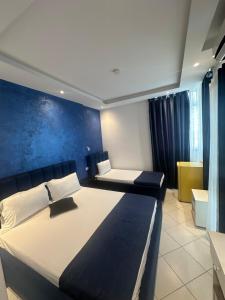 a bedroom with a large bed with a blue wall at Hotel Riviera in Durrës
