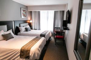 a hotel room with two beds and a television at Apart Hotel Petit Palace Suites in Lima