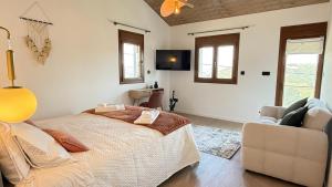 a bedroom with a bed and a couch and windows at River Breeze Douro - Casa Touriga in Marmelal