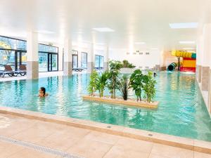 a person swimming in a pool with trees in the water at Camping La Marmotte in Ax-les-Thermes