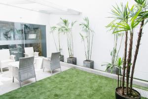 um pátio com palmeiras, cadeiras e relva em Apart Hotel Petit Palace Suites em Lima