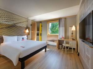 a hotel room with a large bed and a desk at Ibis München City Arnulfpark in Munich +97 photos