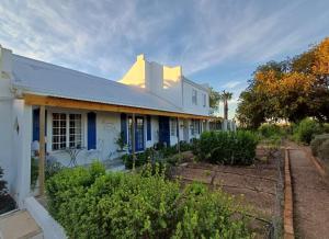 a white house with blue trim and a garden at Rosemarys Cottage in Koringberg